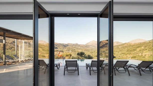 A modern outdoor terrace with a pool, lounge chairs, and a mountain view. - Kourtaliotis Villa Crete (Agios Vasileios)