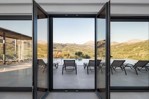 A modern outdoor terrace with a pool, lounge chairs, and a mountain view.
