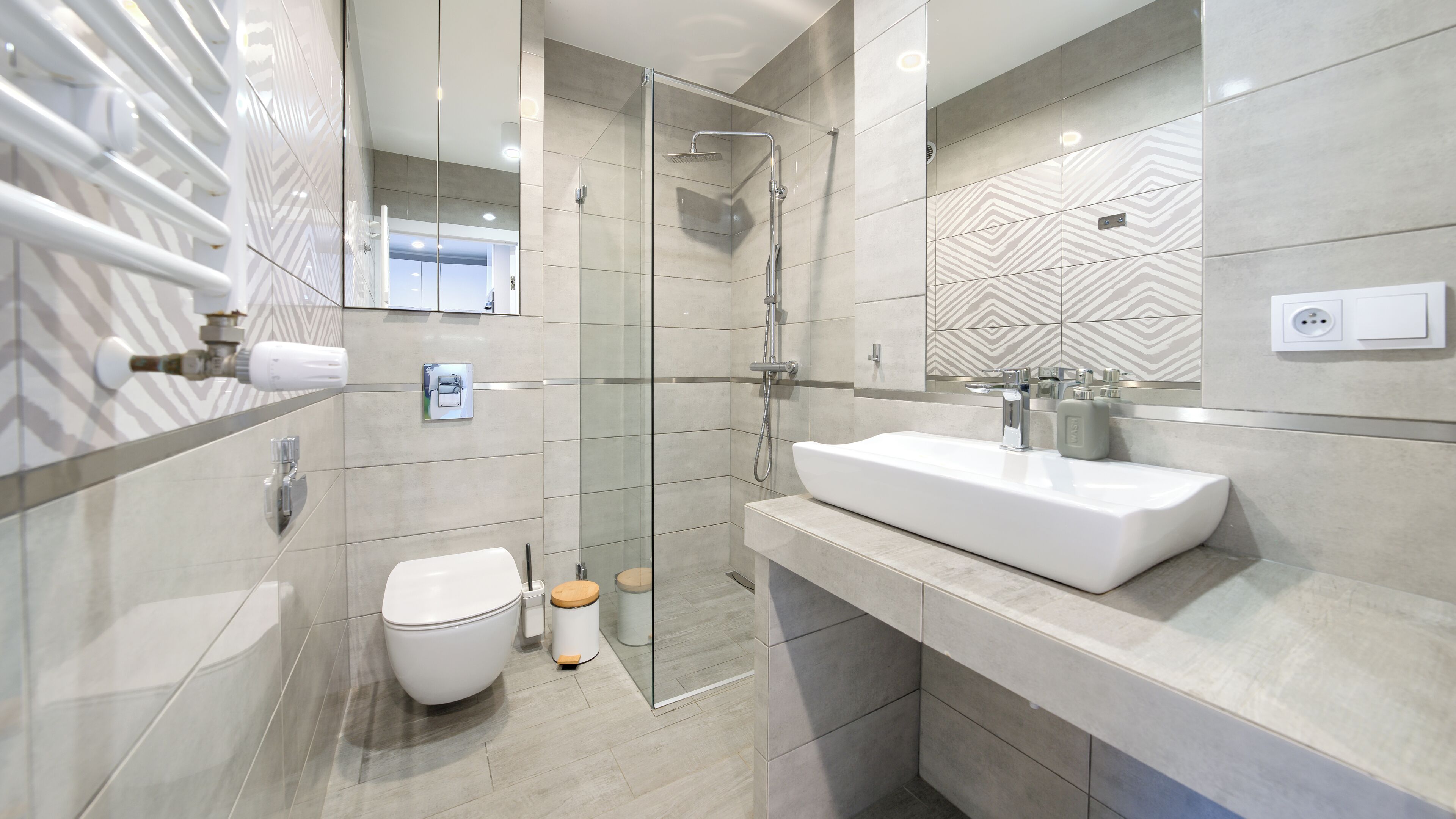 Un baño moderno con ducha de vidrio, lavabo blanco y retrete.