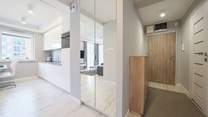 A modern kitchen with white cabinets, a built-in oven, and a window overlooking a cityscape. - Apartamenty Sun & Snow Leśne Tarasy (Dziwnówek)
