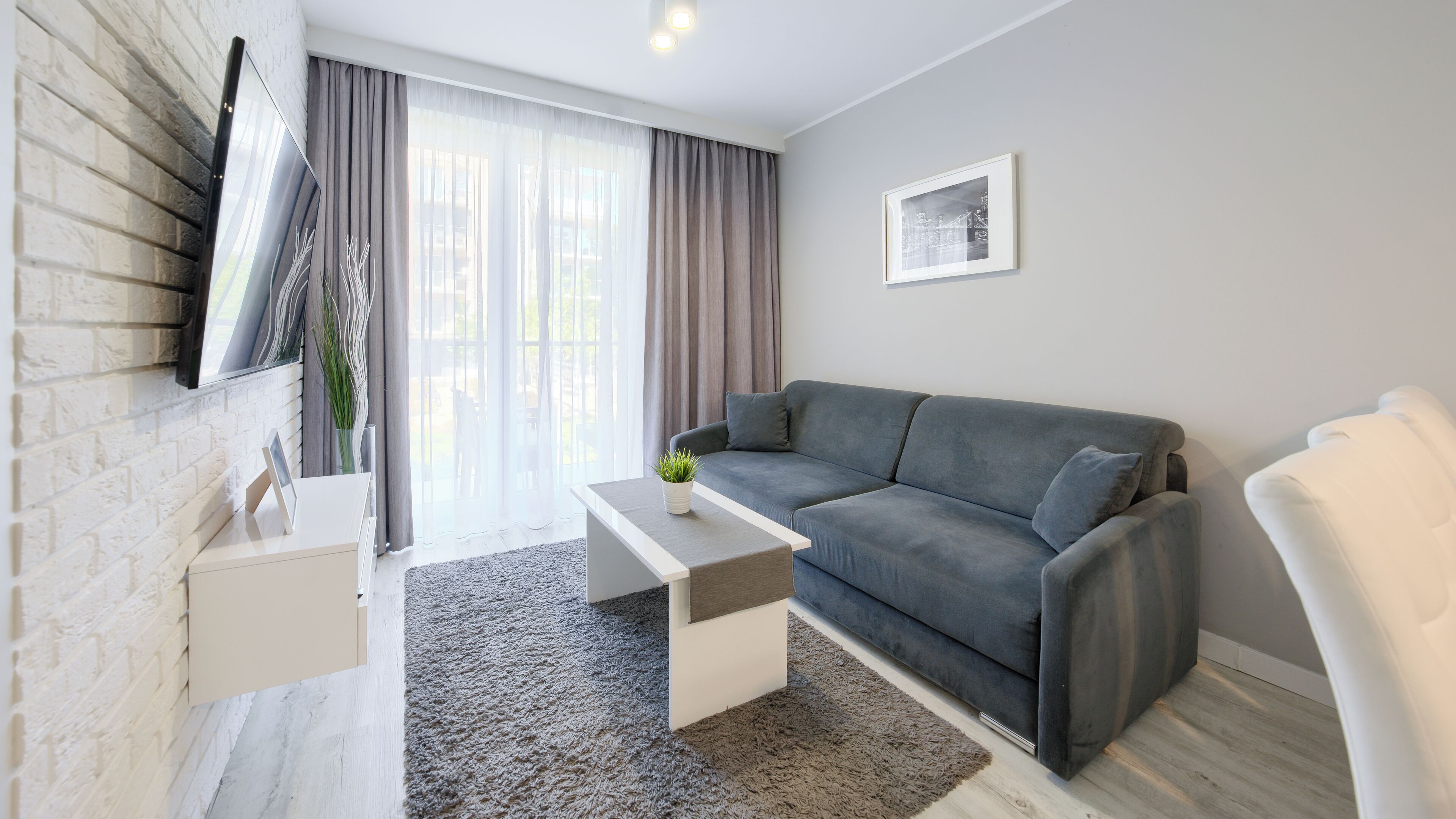 Un salon moderne avec un canapé gris, une table basse blanche et un tapis gris.