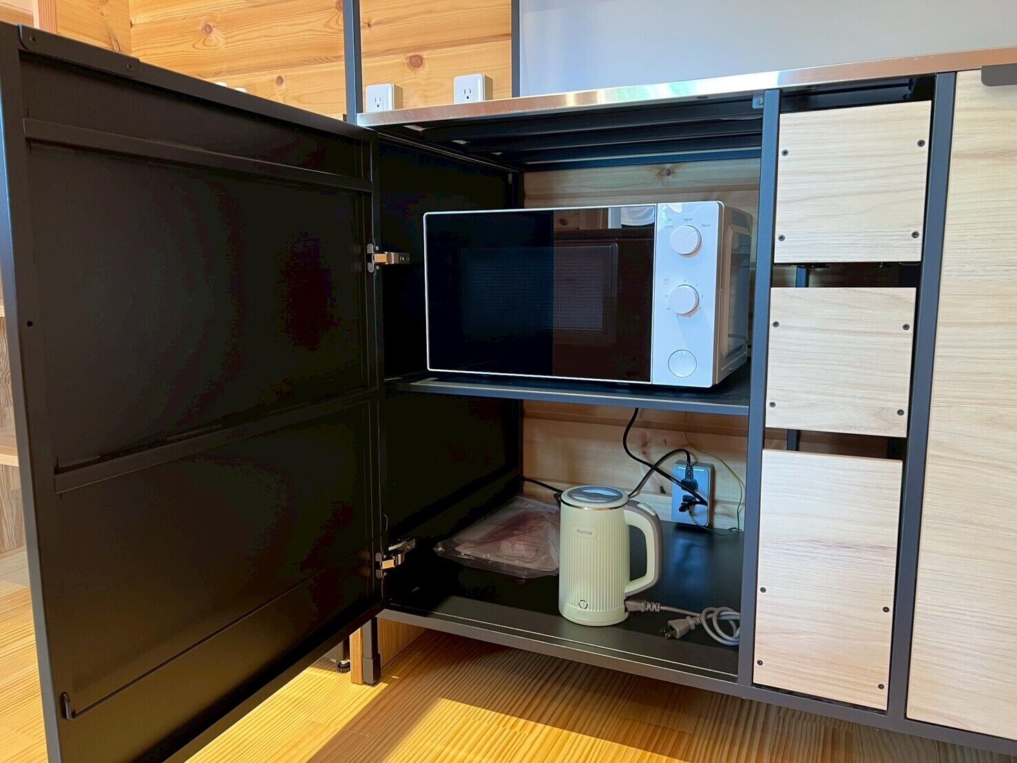 Een praktische keuken met een magnetron, waterkoker en een klein aanrecht.