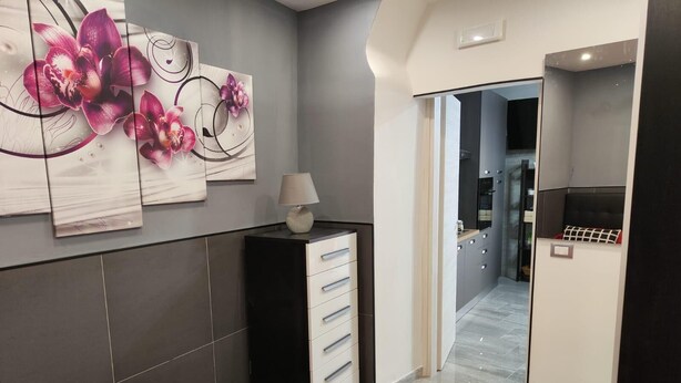 Une chambre d’hôtel moderne avec un lit rouge, une petite table de chevet avec une lampe et des œuvres d’art accrochées au mur.