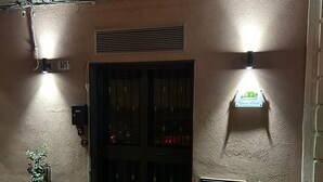 L’entrée d’un parking, avec une voiture garée devant. On y voit une porte dotée d’un clavier de sécurité et une enseigne au-dessus.