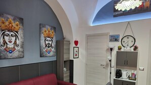 Un salon moderne avec un canapé rouge, une table à manger recouverte d’une nappe orange et deux tableaux accrochés au mur.