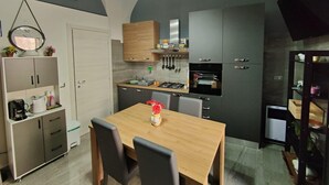 Une cuisine moderne avec un coin repas, comprenant une table en bois, des chaises et un four encastré.