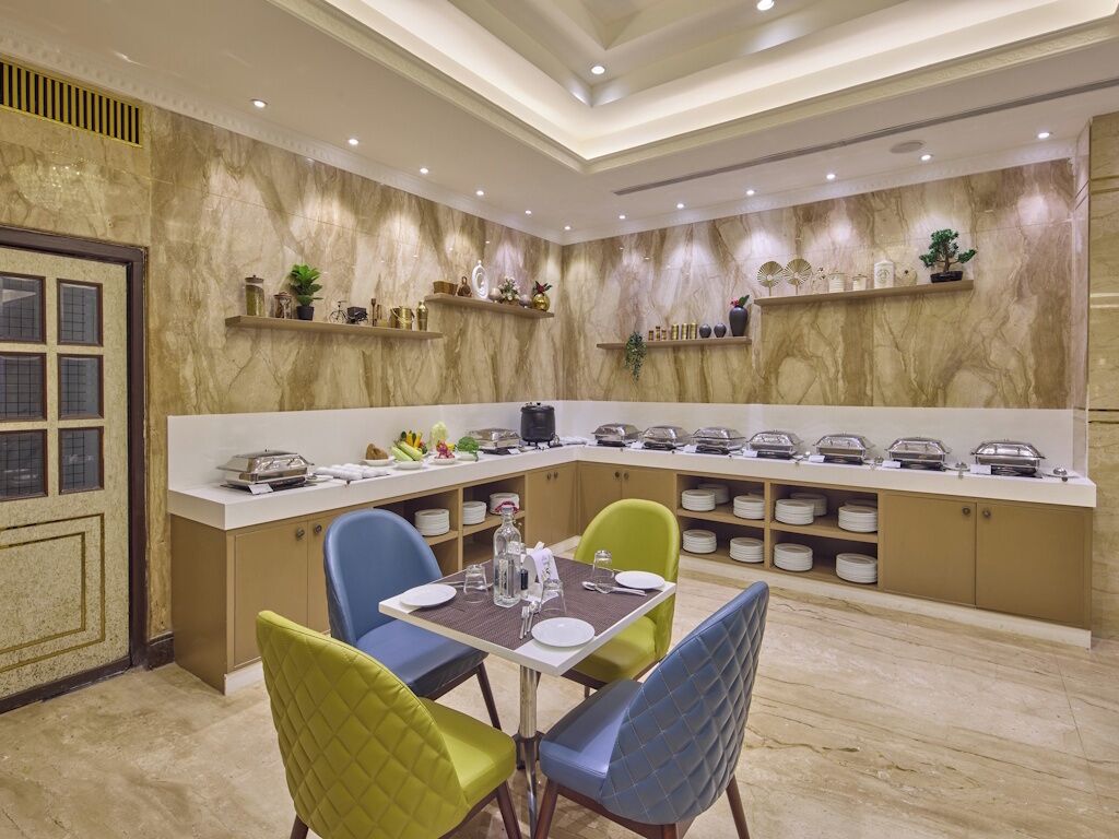 A dining area with a marble wall, a buffet counter, and a seating arrangement with chairs.