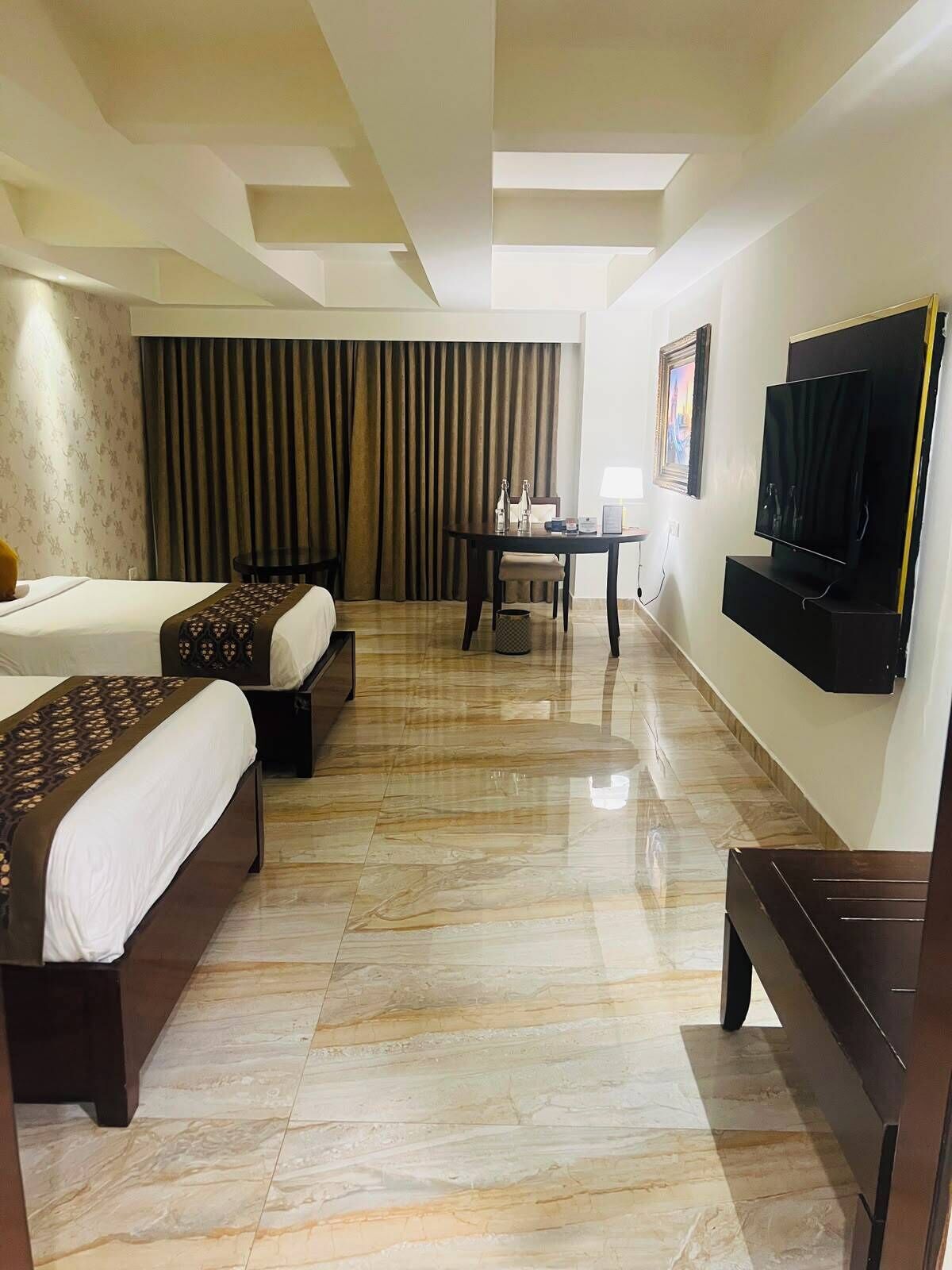 Habitación de hotel con dos camas, televisor, mesa y una silla.