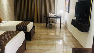 Habitación de hotel con dos camas, televisor, mesa y una silla.