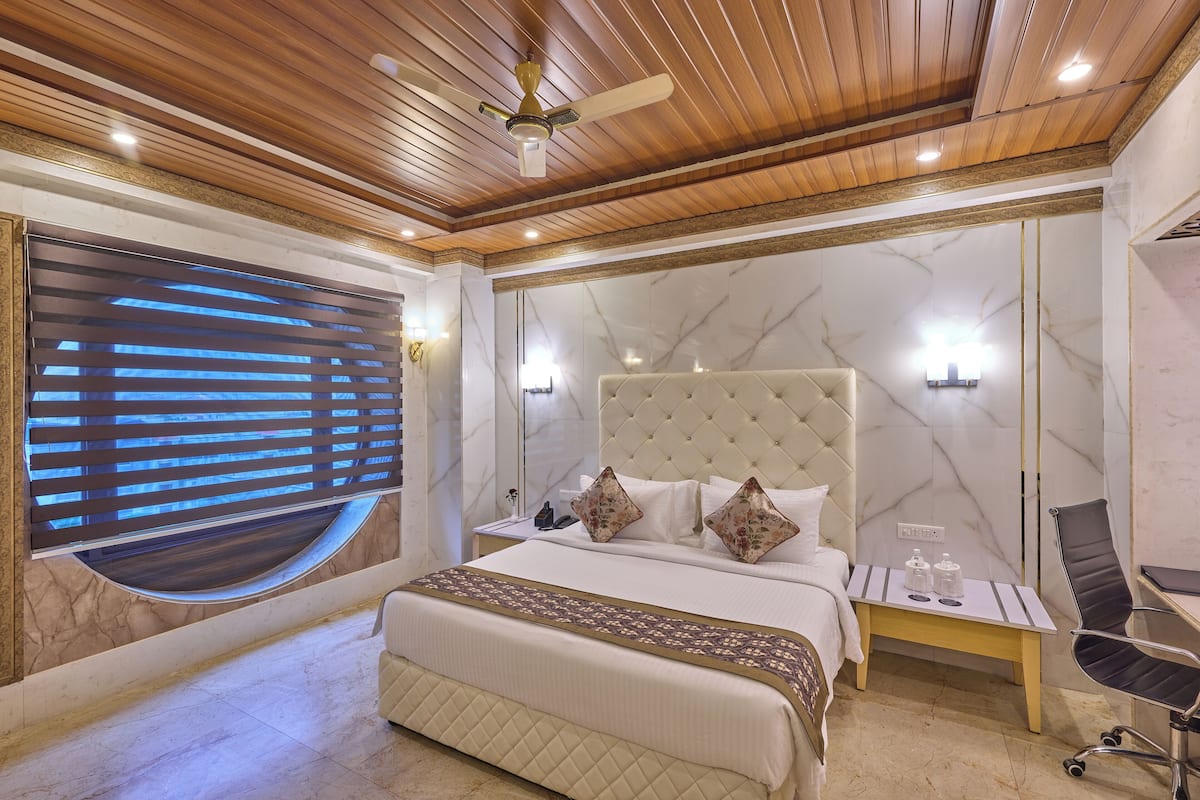 Un dormitorio con cama, mesita de noche, silla y ventilador de techo.