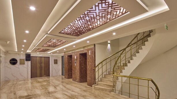 A spacious lobby with a marble floor, a staircase with a metal railing, and a patterned ceiling design. - Grand Continent Premiere - T Nagar (Chennai)