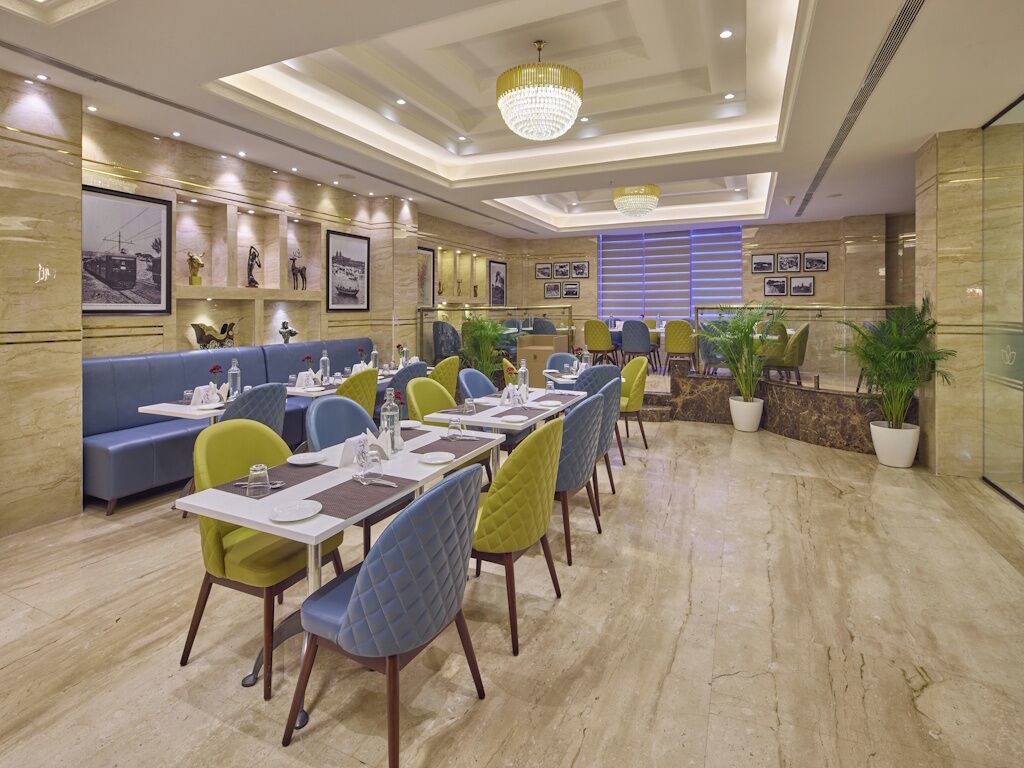 A dining area with tables and chairs, a chandelier, and wall-mounted pictures.