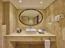 Un baño con tocador de mármol, un espejo grande, un secador de pelo y un perchero para toallas.