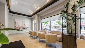 A modern lobby with a large window, a ship painting, and a potted plant. - Hotel Aquila D (Durrës)