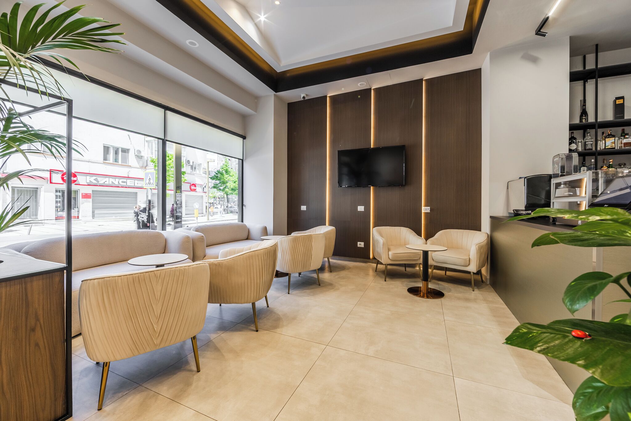 Un moderno vestíbulo de hotel con un sofá, sillas, un televisor y una recepción.