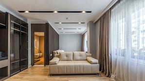 A modern living room with a sofa, a walk-in closet, and a bathroom visible through an open door. - Hotel Aquila D (Durrës)
