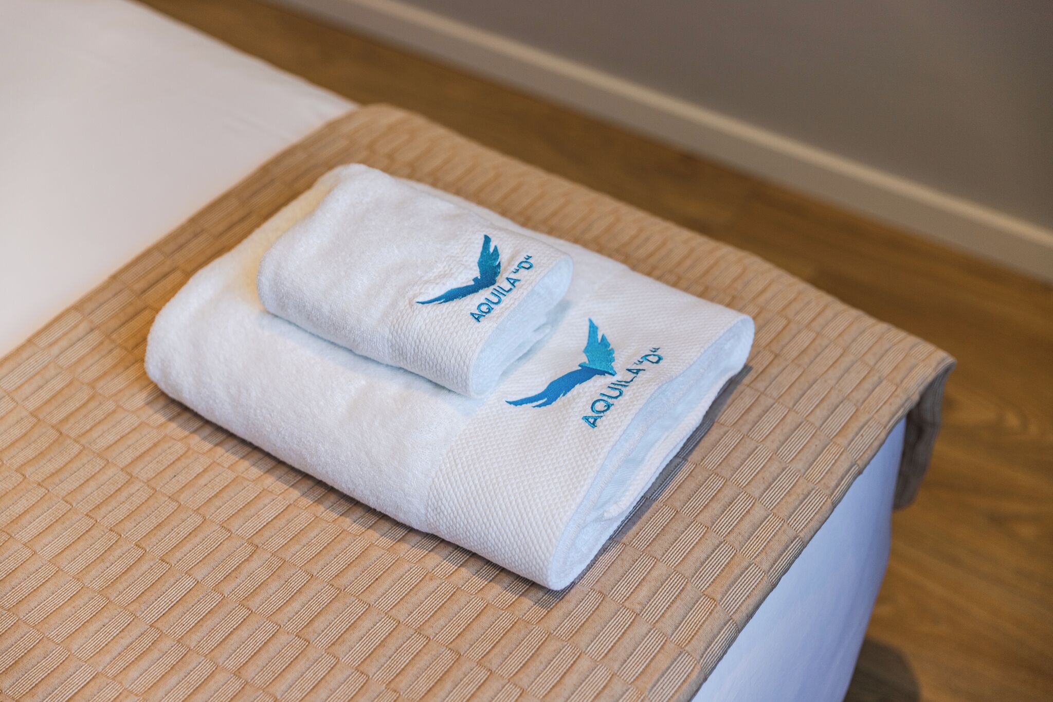 A neatly folded towel with 'AQUILA' branding on a textured surface.