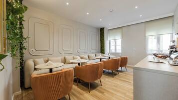 A modern interior with a sofa, round tables, and a bar area.