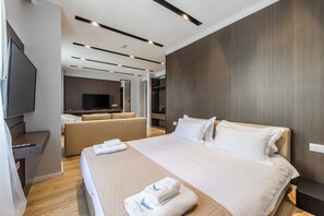A modern hotel room with a large bed, a TV, a sofa, and a walk-in closet. - Hotel Aquila D (Durrës)