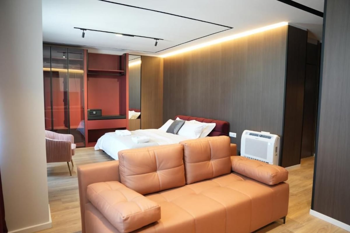 Een moderne hotelkamer met een bed, een bank, een bureau en een inloopkast.