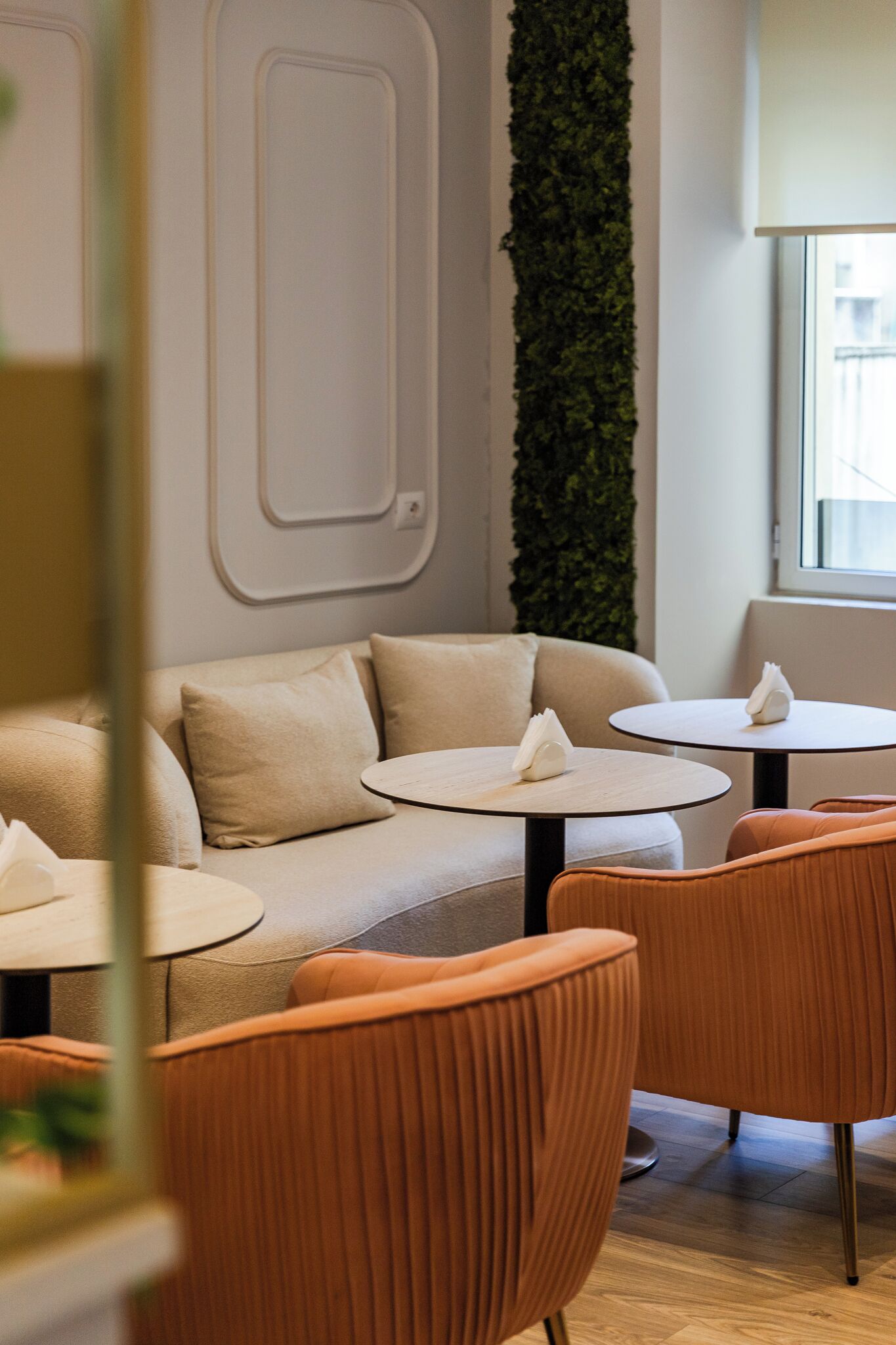 Ein modernes Interieur mit einer Couch, zwei runden Tischen und orangefarbenen Stühlen.