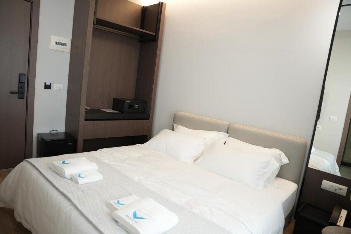 Una camera d'albergo con un letto, un armadio, un comodino e uno specchio.