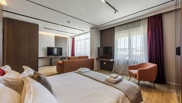 Habitación de hotel moderna con una cama grande, un área de descanso, televisión y vistas a la ciudad.