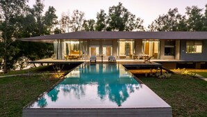 A modern house with a swimming pool, outdoor seating, and a well-maintained garden. - Nature's Island (Trimbak)