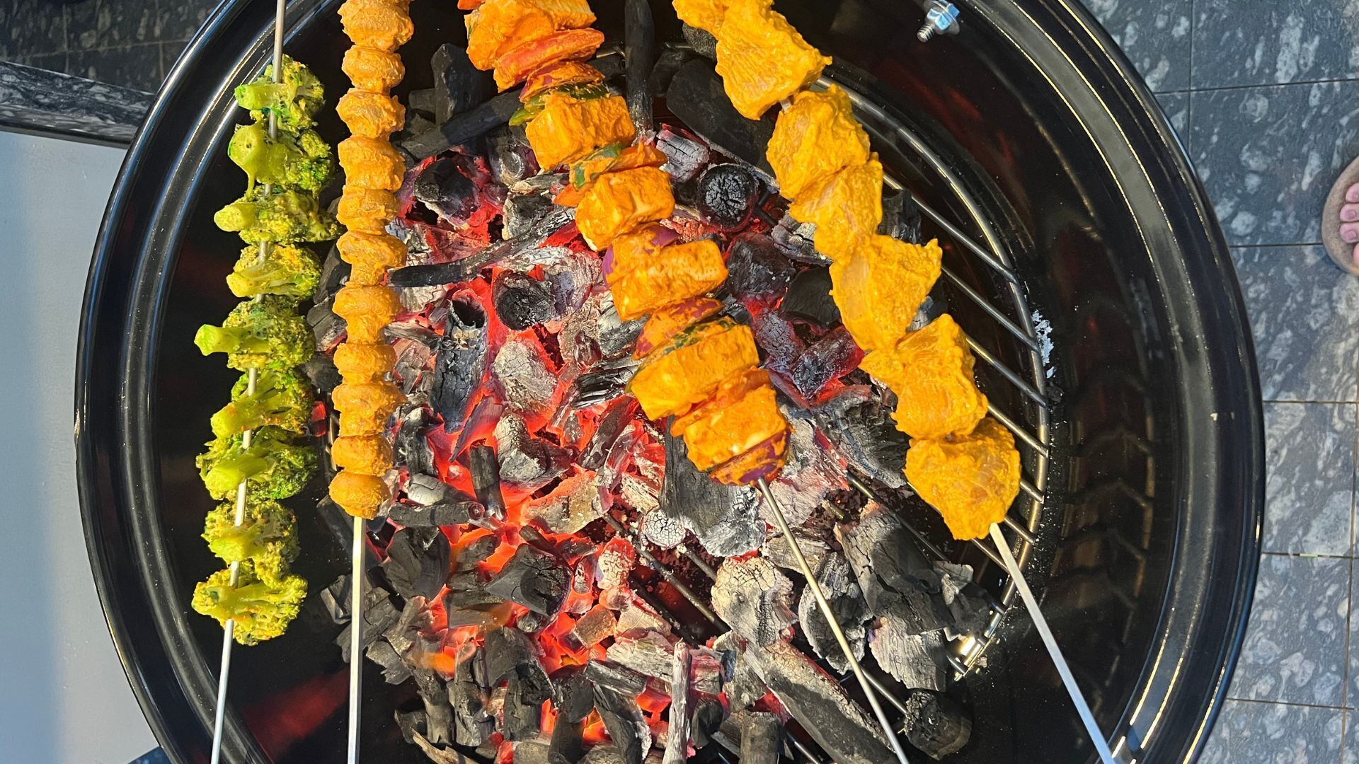 A grill with skewers of vegetables and meat over charcoal.