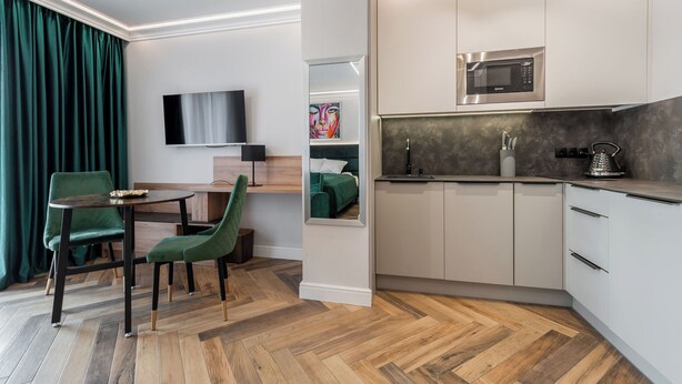 Une chambre d’hôtel moderne dotée d’un coin repas, d’une télévision à écran plat, d’un four à micro-ondes et d’une kitchenette.