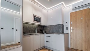 Une cuisine moderne avec des meubles blancs, un four à micro-ondes et une porte en bois.
