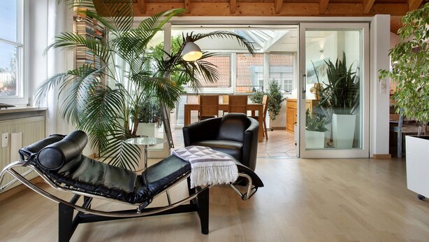 A modern living room with a lounge chair, a dining area, and large windows. - Holiday Apartment Seemöwe with Conservatory, Balcony and Wi-Fi (Kressbronn am Bodensee)