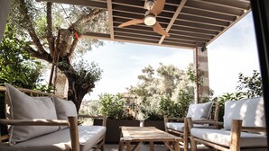An outdoor patio with wooden furniture, a ceiling fan, and potted plants.