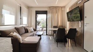 A modern living room with a sofa, chairs, a table, and a TV mounted on the wall.