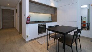Eine moderne Küche mit weißen Schränken, einem Gasherd und einem Essbereich mit Tisch und Stühlen.