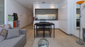 Ein modernes Wohnzimmer mit einer Couch, einem Glastisch und einem Essbereich mit Tisch und Stühlen.