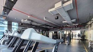Ein Fitnessstudio mit Laufbändern, Trainingsgeräten und einem großen Fenster, das für natürliches Licht sorgt.