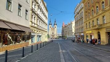 A cobblestone street with historic buildings, a tram line, and a church in the background.