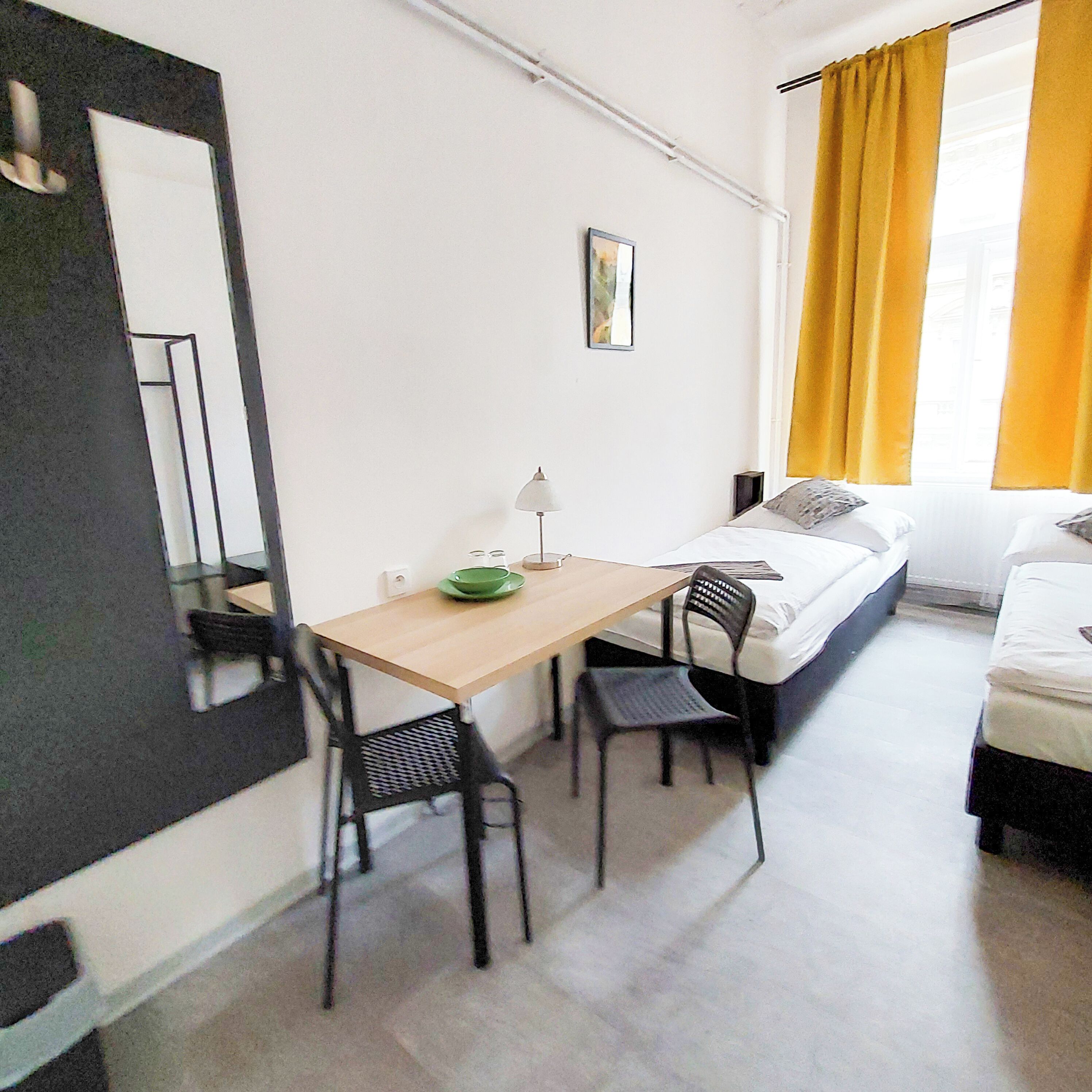 Una stanza piccola e pulita con un letto, una scrivania e due sedie.