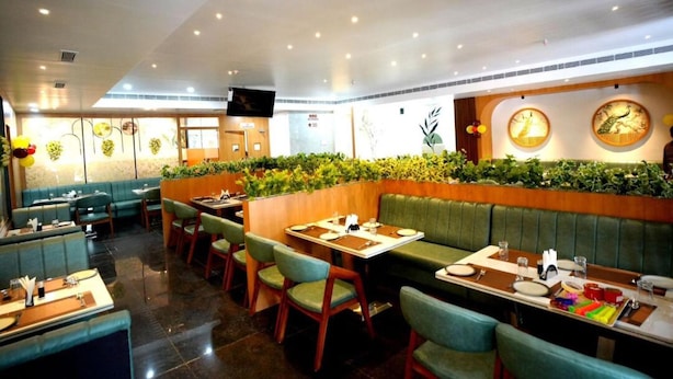 A restaurant with booths and tables, green upholstered seating, and decorative wall panels.