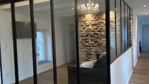 Un intérieur moderne avec un mur d’accent en pierre, un lustre et un plancher en bois.