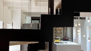 Un intérieur moderne avec une structure centrale noire, des murs blancs et des luminaires suspendus.