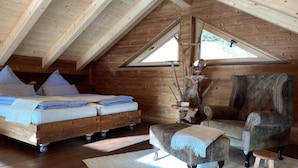 Une chambre confortable située sous les toits, avec un lit en bois, un fauteuil moelleux et un élément de décoration rustique.