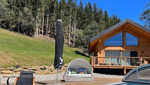 Une cabane en bois avec une piscine, des chaises longues et un espace salon couvert.