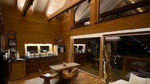 Un vaste espace de vie doté d’un plancher en bois, d’un grand canapé, d’une table à manger et d’une cuisine située à l’arrière-plan.