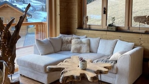 L'intérieur d'un chalet chaleureux, doté d'une grande fenêtre donnant sur un paysage enneigé.