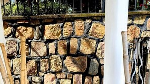 Deux grands vases ornés de tiges de bambou, un mur en pierre et une rambarde en métal.