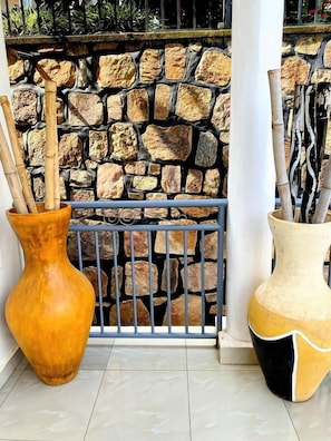 Due vasi grandi con stecchini di bambù, un muro in pietra e una ringhiera metallica.