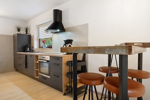Una cocina moderna con una isla central, taburetes de bar y una campana extractora negra.