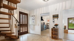 Ein modernes Interieur mit einer Holztreppe, einer Küchenzeile und Blick ins Freie.